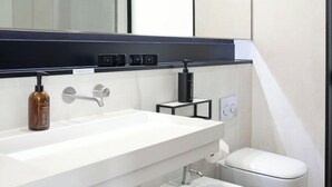 Un baño moderno con un lavamanos blanco, un bidé y un inodoro.