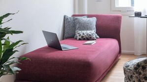 A modern living room with a red sofa, a laptop, and a small table with a camera.