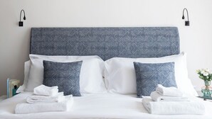 A neatly made bed with a patterned headboard, white pillows, and folded towels. - Penthouse Apartment 5.4 (Milano)