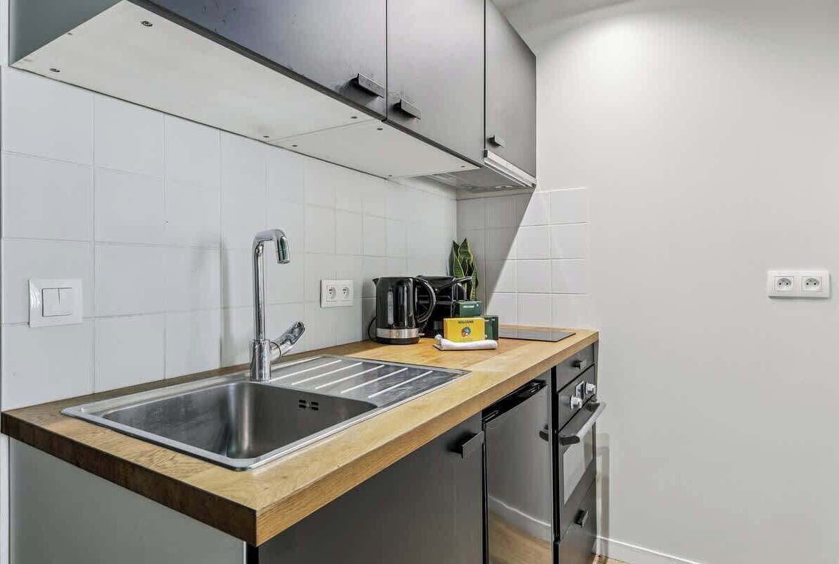 Una cocina moderna con un lavamanos de acero inoxidable, una cafetera y un tostador sobre la encimera.