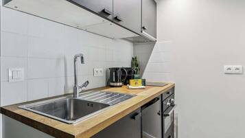 Una cocina moderna con un lavamanos de acero inoxidable, una cafetera y un tostador sobre la encimera.