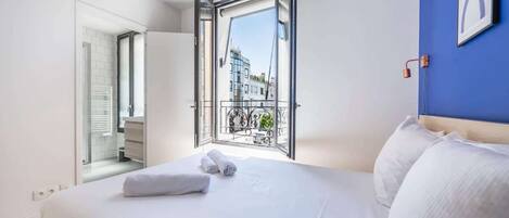Ein Hotelzimmer mit einem großen Bett, Blick auf einen Balkon und einer Tür zu einem Badezimmer.