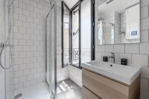 A modern bathroom with a glass shower enclosure, a white sink, and a large mirror. - 10min from Paris | Close to Shops/ 8min from Metro (Boulogne-Billancourt)