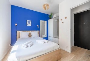 A bedroom with a bed, a wardrobe, a mirror, and a door.