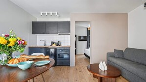 A modern living room with a grey sofa, a wooden coffee table, and a dining area with a wooden table and chairs.