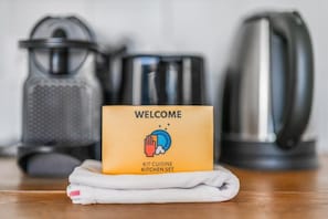 Um letreiro de boas-vindas com um ícone de cozinha, uma chaleira e um ralador sobre uma superfície de madeira.