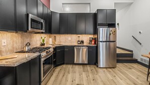 A modern kitchen with black cabinets, stainless steel appliances, a wooden countertop, and a staircase leading to another level. - Old City History Kid-Friendly (Philadelphia)