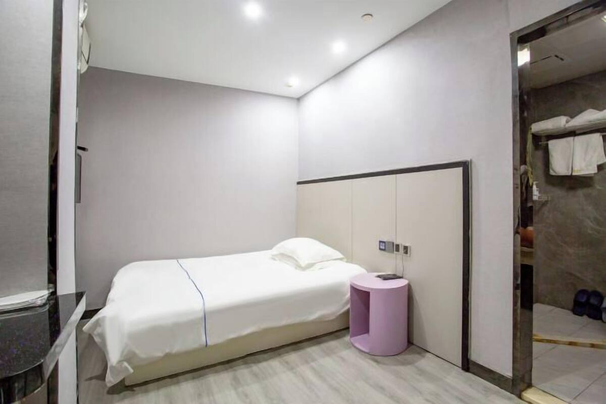 A modern bedroom with a bed, a small round table, and a wardrobe.