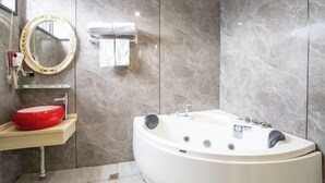 A modern bathroom with a marble wall, a red sink, a white bathtub, and a round mirror. - Yixin Hotel (Shanghai Guilin Road Subway Station) (Shanghai)