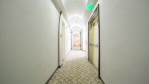 A hotel corridor with a patterned carpet, white walls, and doors on both sides. - Yixin Hotel (Shanghai Guilin Road Subway Station) (Shanghai)