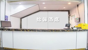 A hotel reception desk with a check-in counter, a computer, and a monitor. - Yixin Hotel (Shanghai Guilin Road Subway Station) (Shanghai)
