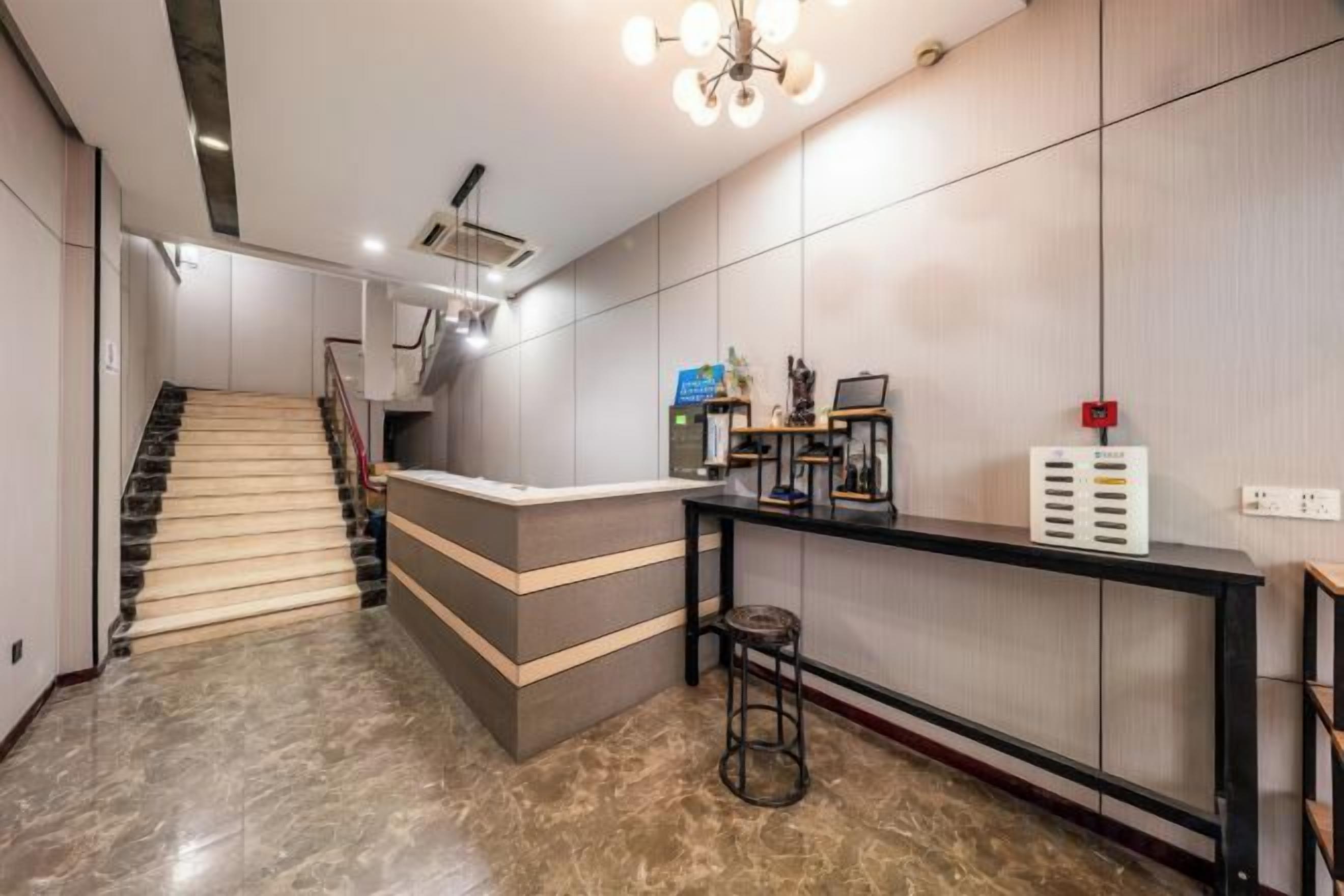 A reception area with a staircase, a reception desk, and a wall-mounted control panel.