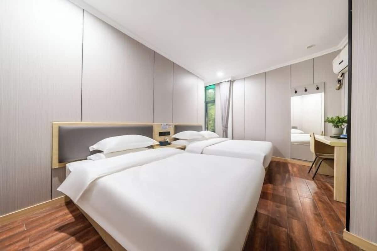 Une chambre d’hôtel avec deux lits, un bureau et un miroir.