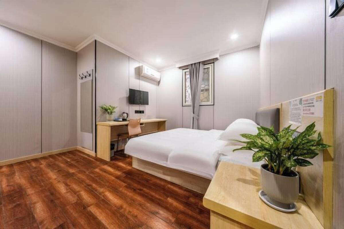 Une chambre d’hôtel équipée d’un lit, d’un bureau, d’une chaise, d’une plante en pot et d’un téléviseur à écran plat.