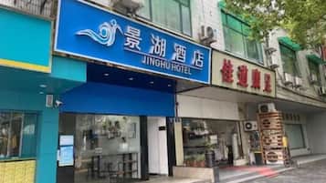 A hotel with a blue sign, a visible entrance, and a storefront with a stack of items outside.