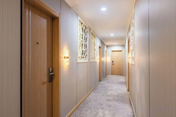 A hotel hallway with wooden doors, decorative panels, and recessed lighting. - Jinghu Hotel (Hangzhou Hefang Street Branch) (Hangzhou)