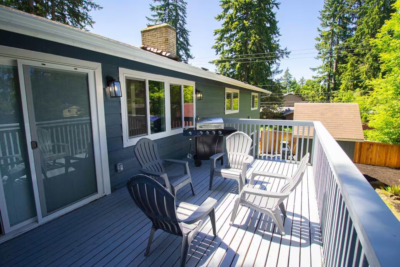 A deck with outdoor seating, a grill, and a sliding glass door.