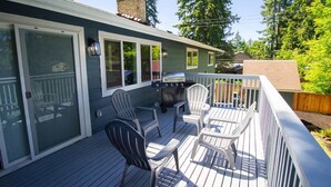 A deck with outdoor seating, a grill, and a sliding glass door.