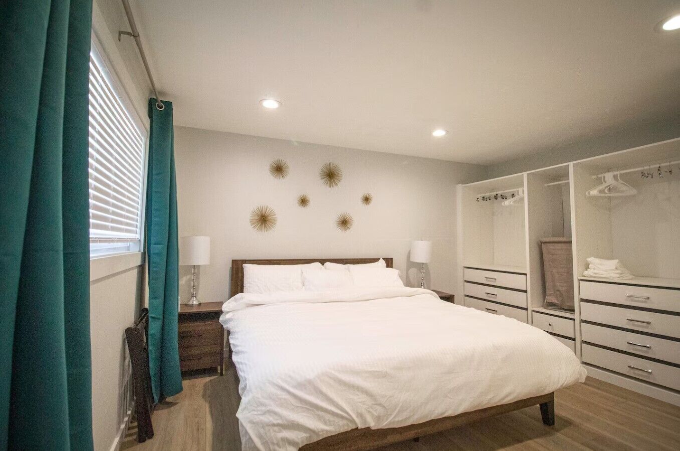 A bedroom with a bed, bedside tables, a wardrobe, and a window with curtains.