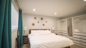 A bedroom with a bed, bedside tables, a wardrobe, and a window with curtains.