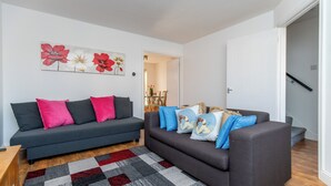 A modern living room with two sofas, a patterned rug, and a floral artwork on the wall.