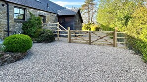A stone building with a wooden gate and gravel driveway.