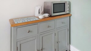A kitchen with a microwave, kettle, and a coffee cup on a wooden countertop. - 1 bedroom accommodation in Walcott (Walcott)