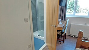 A room with a wooden wardrobe, a glass shower enclosure, a dining table with chairs, and a window with a view of trees. - 1 bedroom accommodation in Walcott (Walcott)