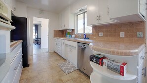 A modern kitchen with white cabinets, a stainless steel dishwasher, and a beige countertop.
