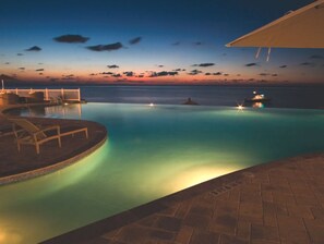 An infinity pool with a view of the ocean at dusk. - Bimini Bay 2BR - Beach, Pool + Sunset Views (Bailey Town)