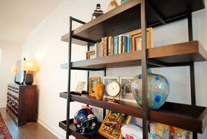 Ein Bücherregal mit verschiedenen Dekorationselementen, darunter Bücher, eine Uhr und ein Sporthelm.