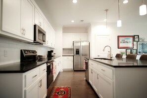 A modern kitchen with white cabinetry, stainless steel appliances, and a central island with a sink. - Luxurious Property in the Heart of Oxford (Oxford)