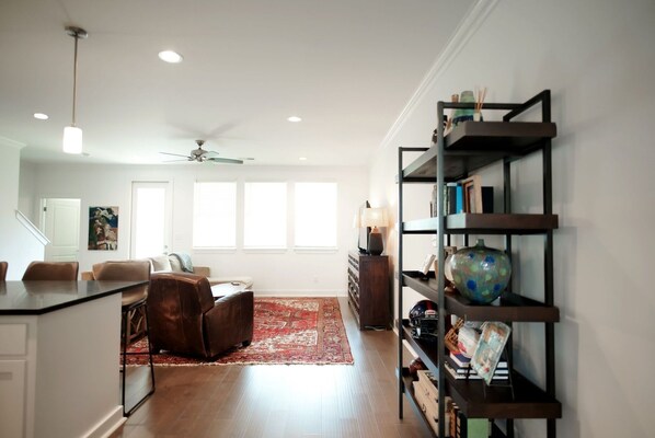 A modern living room with a red rug, a brown leather sofa, a coffee table, and a bookshelf with various items. - Luxurious Property in the Heart of Oxford (Oxford)