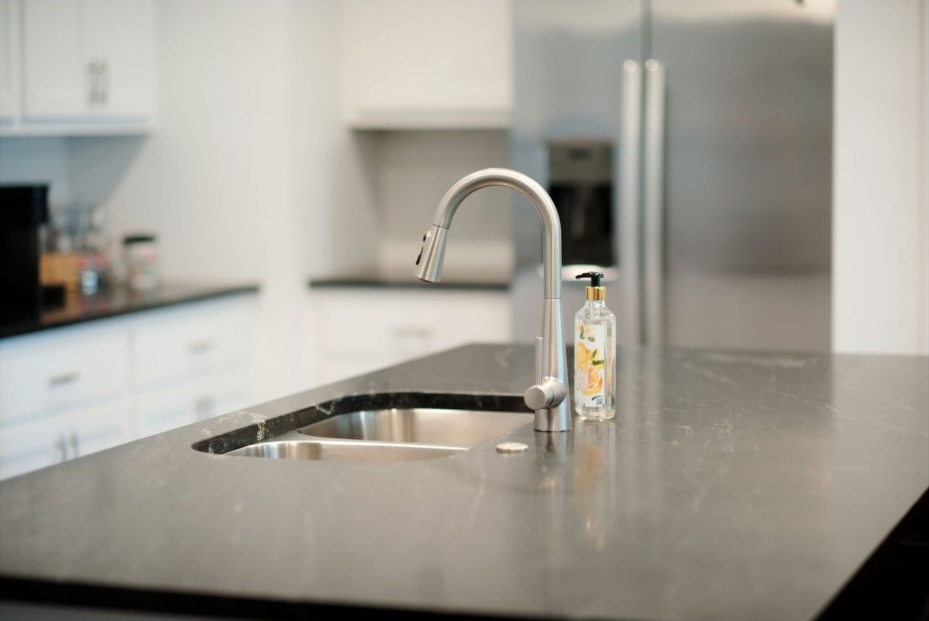 Een moderne keuken met een roestvrijstalen spoelbak, een kraan en een zeepdispenser.