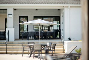 An outdoor seating area with tables and chairs, a covered umbrella, and a white building with large windows in the background. - Luxurious Property in the Heart of Oxford (Oxford)