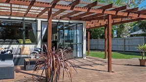 Un patio techado con mobiliario exterior y una estructura de pérgola.