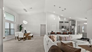 A spacious living area with a large sofa, dining table, and kitchen in the background. - Paradise in front of the water (Cape Coral)