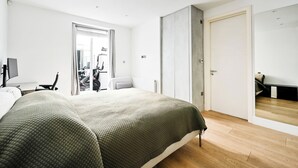 Una habitación de hotel moderna con una cama grande, un escritorio y un espejo.