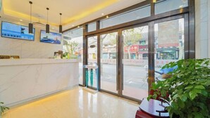 A hotel lobby with a reception desk, large windows, and a plant. - Xiangfu Hostel (Shanghai Wuning Road) (Shanghai)