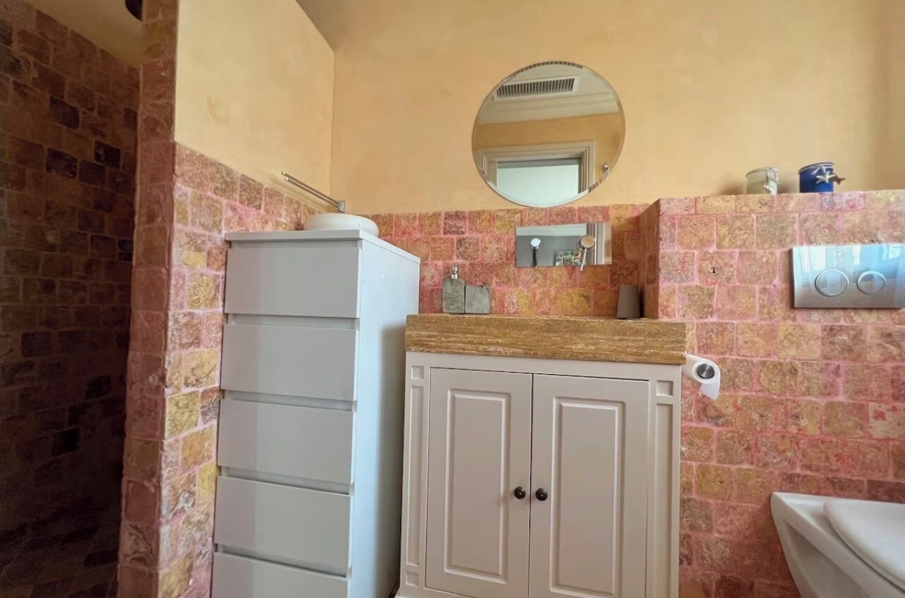 A bathroom with a white cabinet, a mirror, and a toilet.