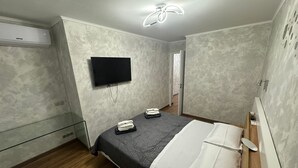 A modern bedroom with a bed, a flat-screen TV, and a ceiling fan. - Apartament with sea wiev (Nice)