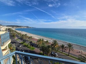 Un paysage urbain côtier avec une plage, des palmiers et une route menant à la plage.