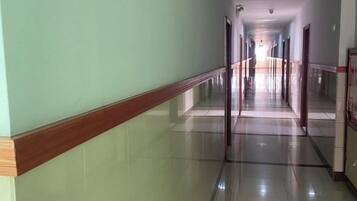 Un pasillo largo y recto con piso reflectante y zócalo de madera.