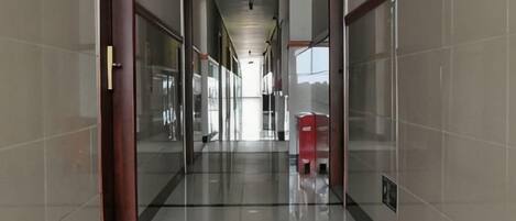 A corridor with glass doors, a red mailbox, and a tiled floor.