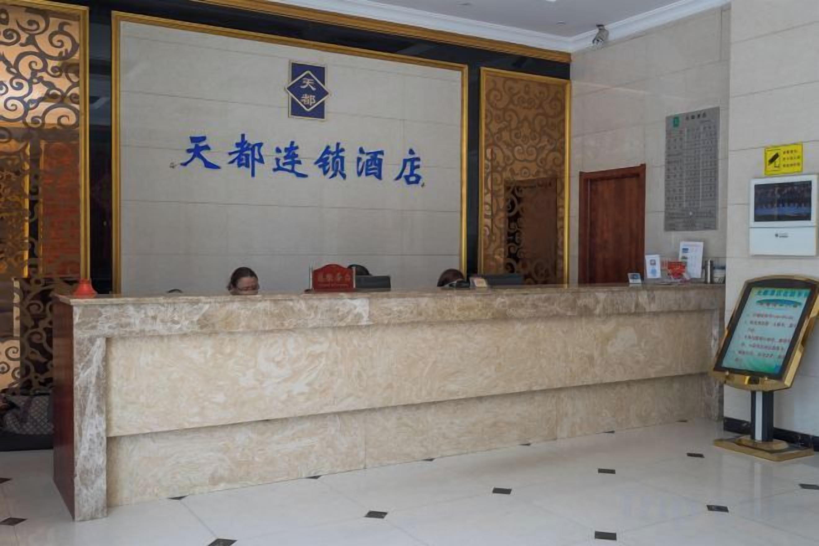 Un mostrador de recepción de hotel con encimera de mármol y un cartel arriba.