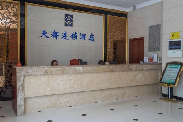 Un mostrador de recepción de hotel con encimera de mármol y un cartel arriba.