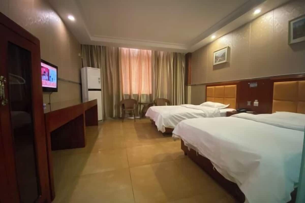 Quarto de hotel com duas camas, televisão, escrivaninha e uma cadeira.