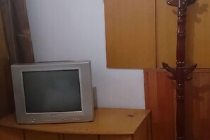 A television on a wooden stand in a room with a wooden cabinet and a coat rack. - Jinying Hostel (Shanghai)