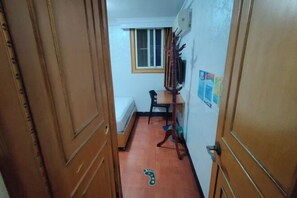 A narrow hallway with a wooden door, a window, a chair, and a small table. - Jinying Hostel (Shanghai)