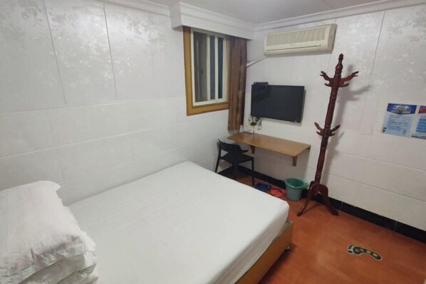 A small, clean room with a single bed, a desk with a chair, a TV mounted on the wall, and a coat rack. - Jinying Hostel (Shanghai)